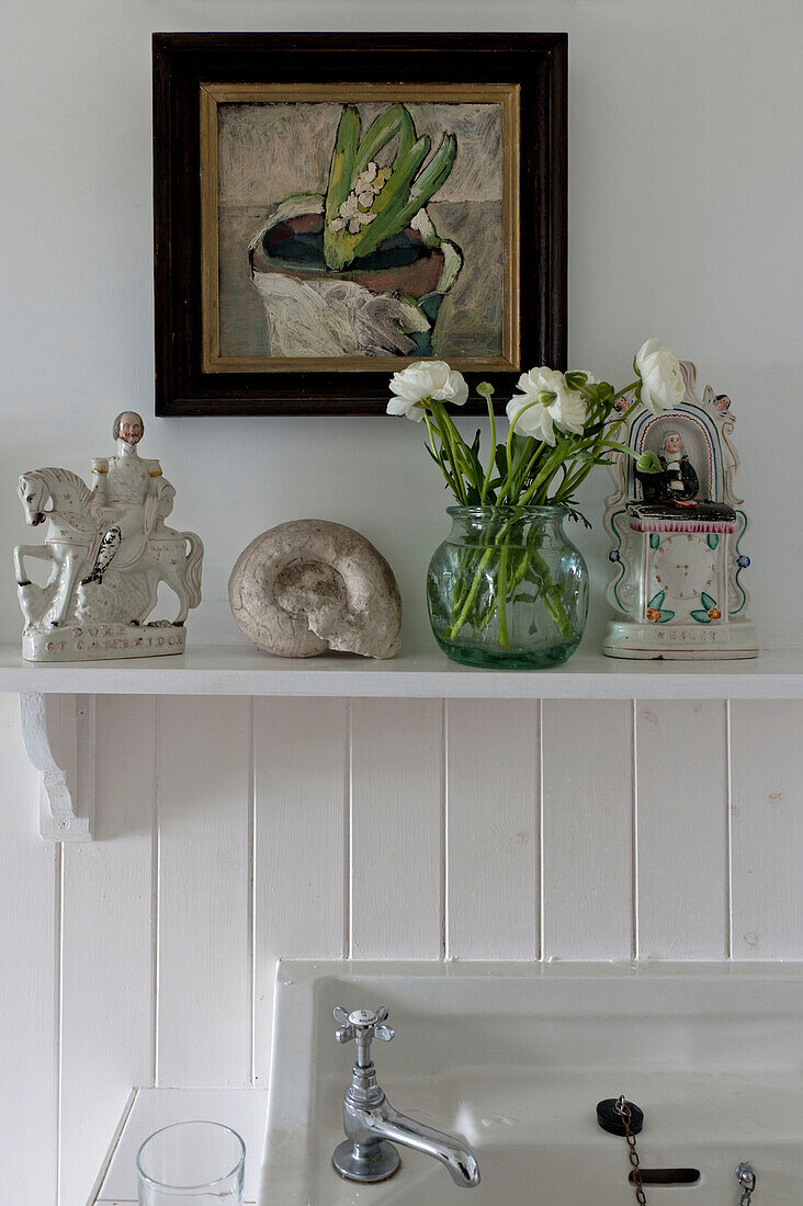 camellias and figurines on shelf above washbasin in beach house Cornwall England UK
