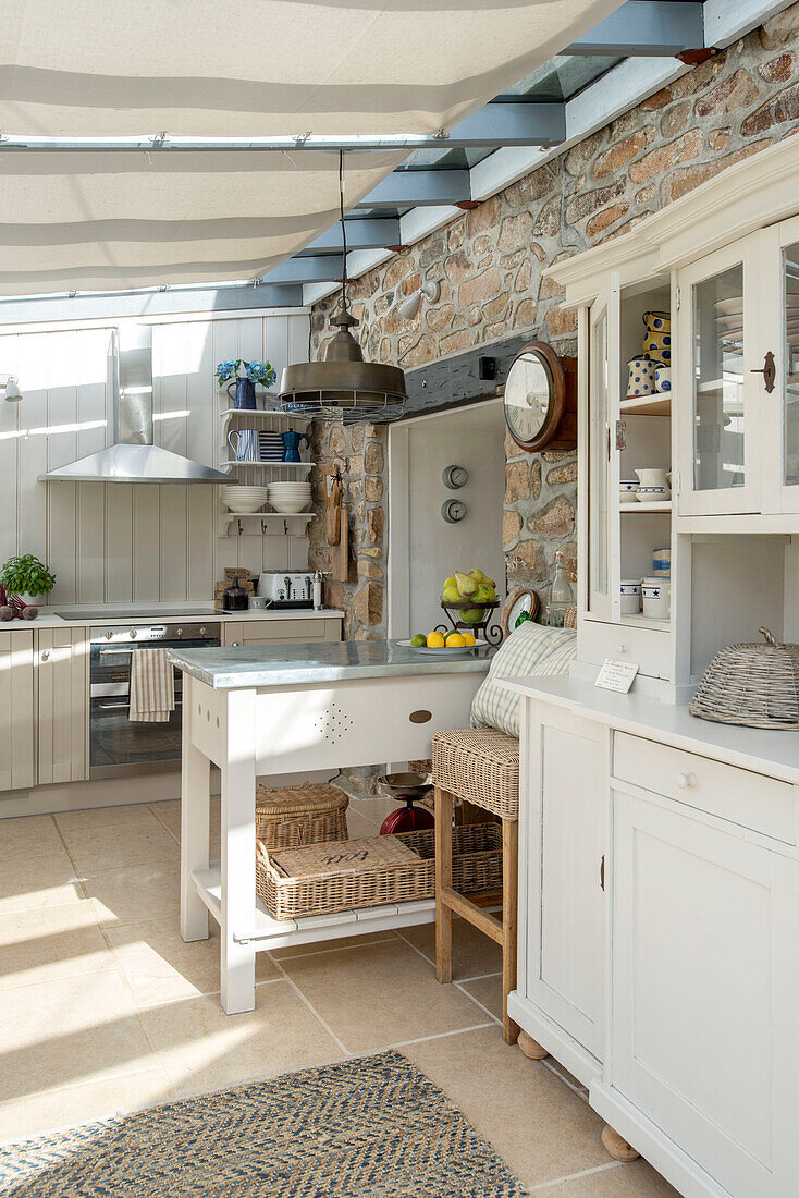 Weiße Küchenkommode mit freiliegender Steinwand in Küchenerweiterung eines Bauernhauses in Penzance, Cornwall, England, UK