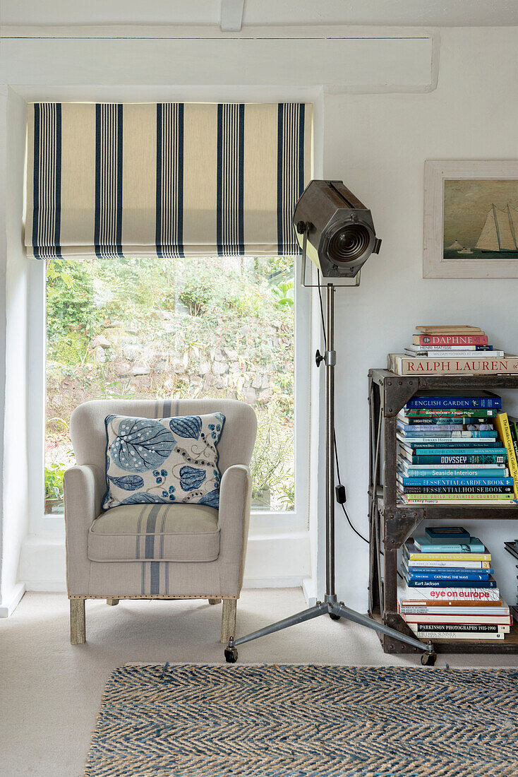 Sessel mit Scheinwerfer und Bücherregal am Fenster eines Bauernhauses in Penzance Cornwall England UK