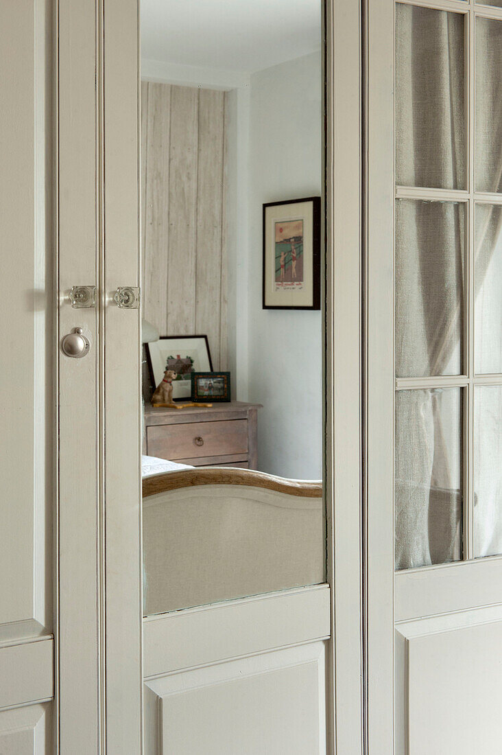 Bedside chest reflected in mirrored wardrobe in Penzance farmhouse Cornwall England UK
