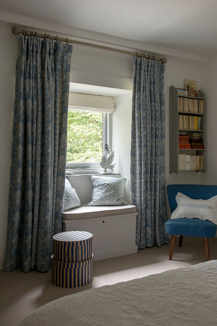 Blue patterned curtains and window seat in bedroom of Penzance farmhouse Cornwall England UK