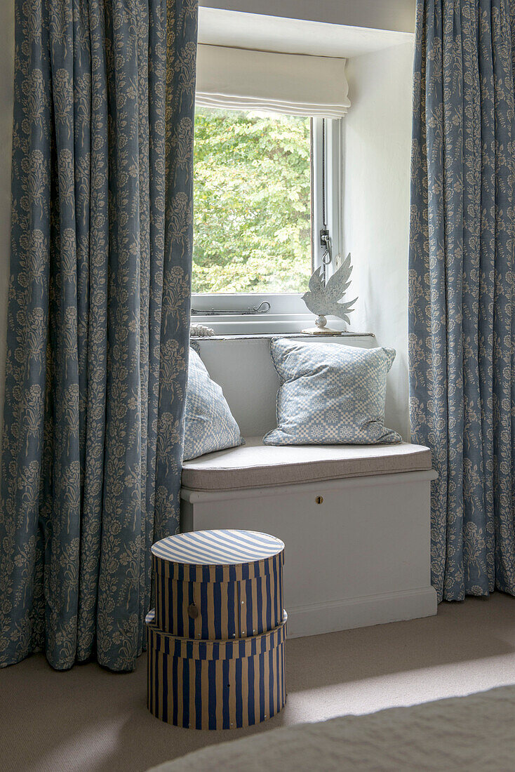 Blue patterned curtains and window seat in bedroom of Penzance farmhouse Cornwall England UK