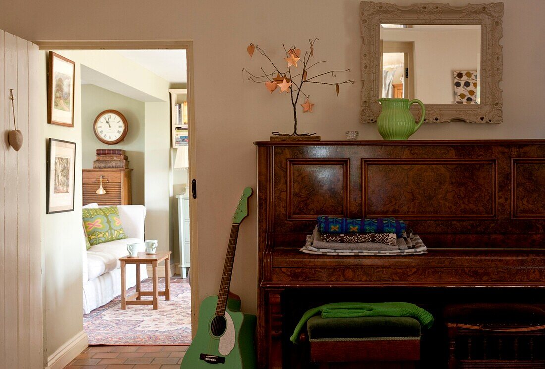 Grüne Gitarre und Klavier mit Blick durch die Tür zum Edworth-Wohnzimmer Bedfordshire England UK