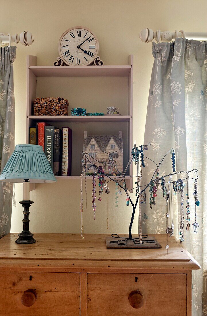 Jewellery stand on wooden sideboard with wall mounted shelf unit in Edworth cottage Bedfordshire England UK