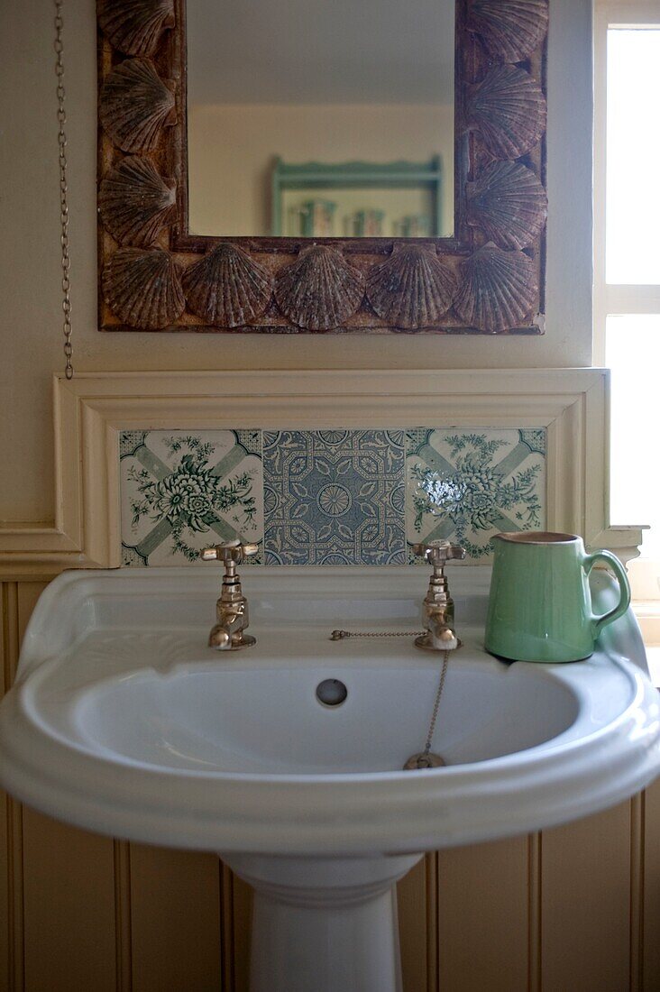 Light green ceramic jug on tiled pedestal washbasin in Edworth bathroom Bedfordshire England UK