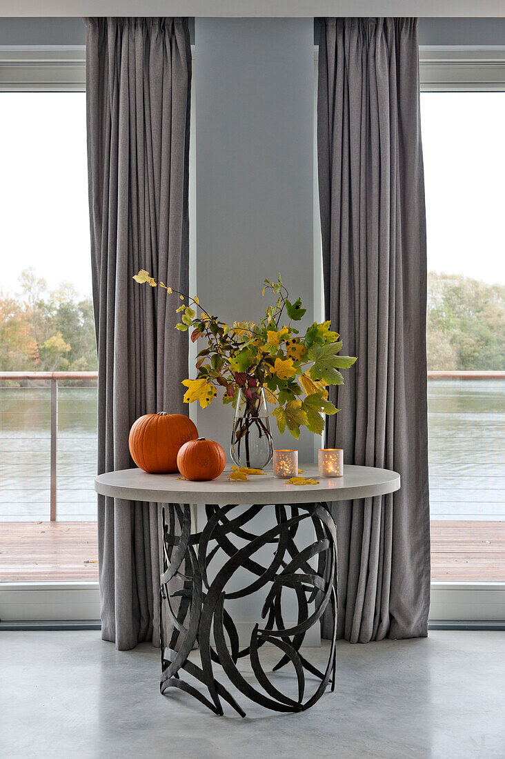 Cut flowers and pumpkins on metalworked side table in Lechlade living room Gloucestershire England UK