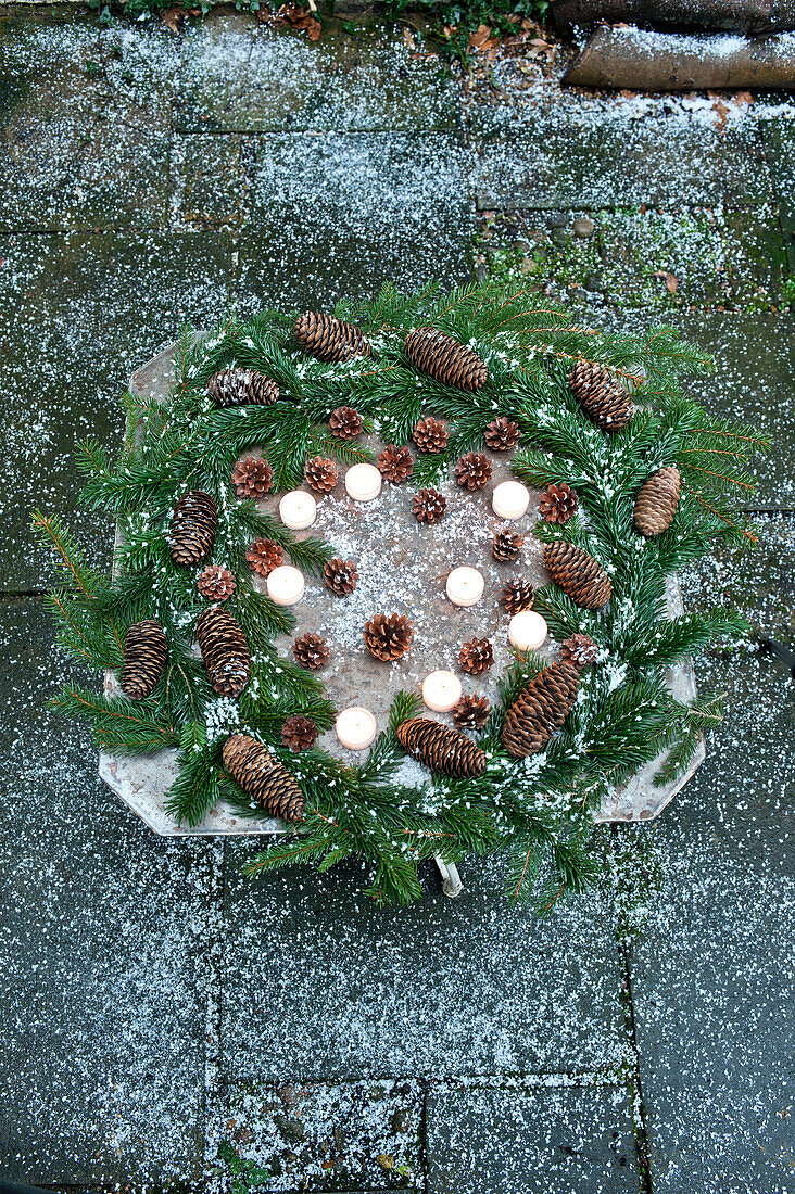 A table wreath made with a whole variety of spruce fir cones and candles makes a lovely Christmas display both outside and in