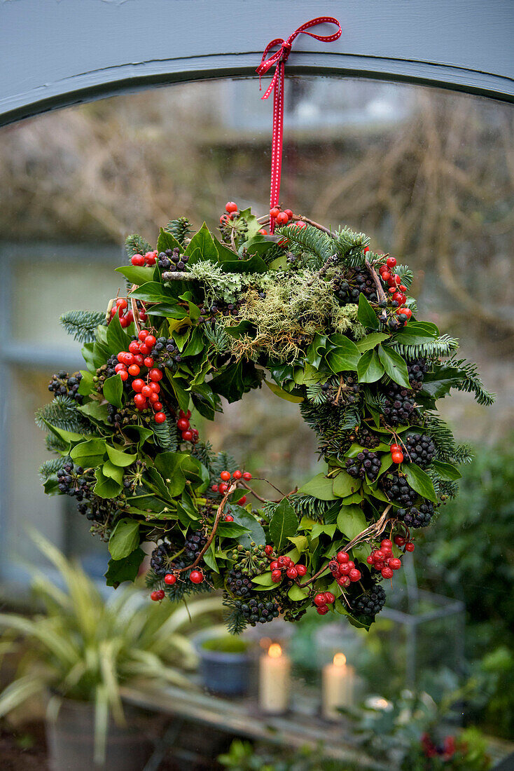 Christmas wreath made of leaves and berries in window of Penzance home Cornwall UK