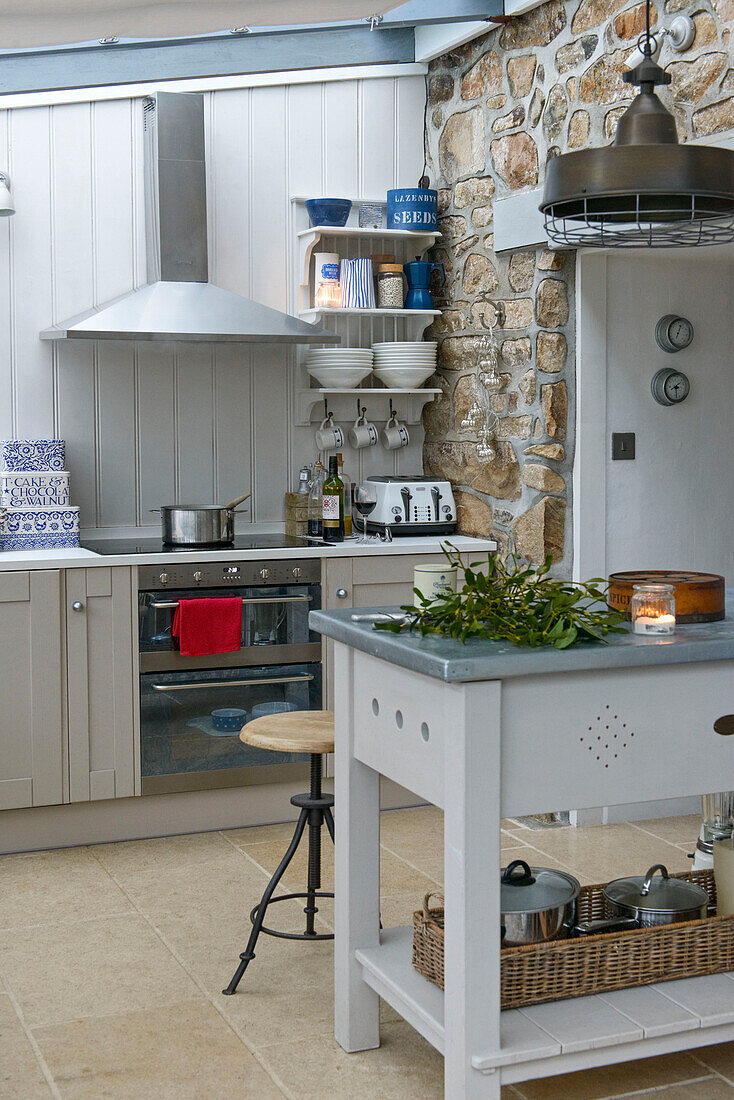 Butchers block and stool in exposed stone farmhouse kitchen with saucepan on hob Penzance Cornwall UK