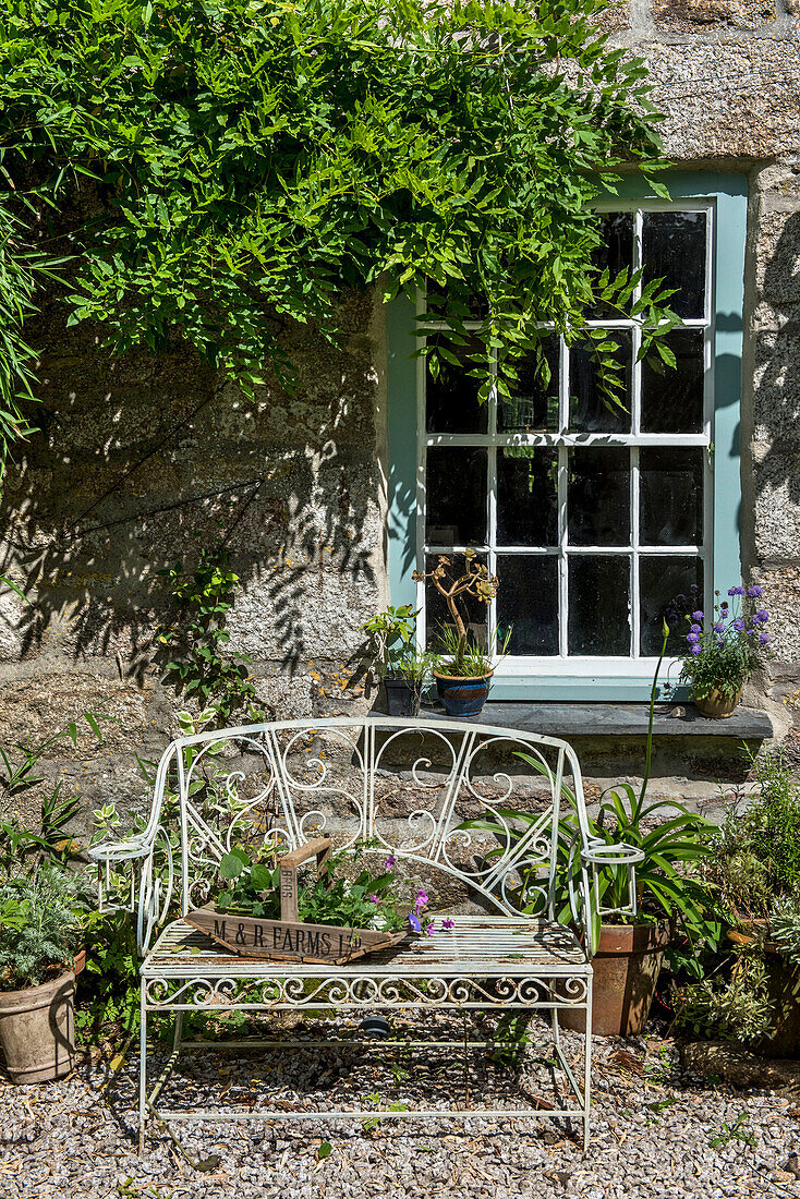 Gartengerät auf einer Bank mit Metallrahmen im Garten eines Hauses in Helston, Cornwall, UK