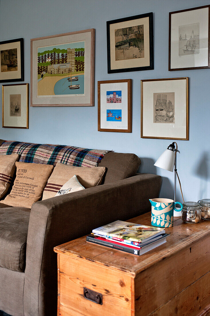 Kunstwerk-Display über braunem Sofa mit Kissen im Wohnzimmer eines Ferienhauses in Cornwall England