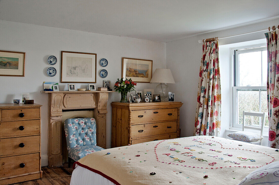 Bettdecke aus Nadelspitze mit Holzkisten in einem Cottage-Schlafzimmer mit geblümten Vorhängen Cornwall UK