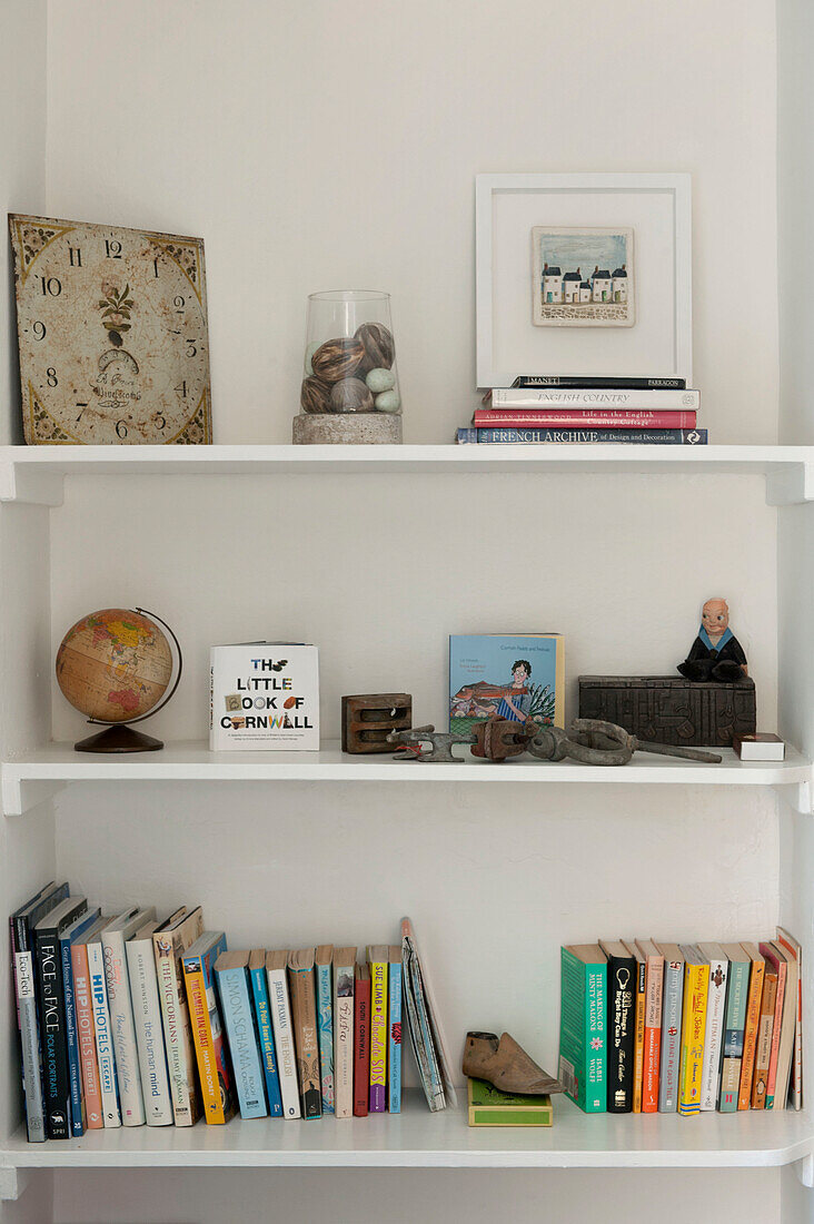Books and ornaments on white shelving uit in Cornwall cottage UK