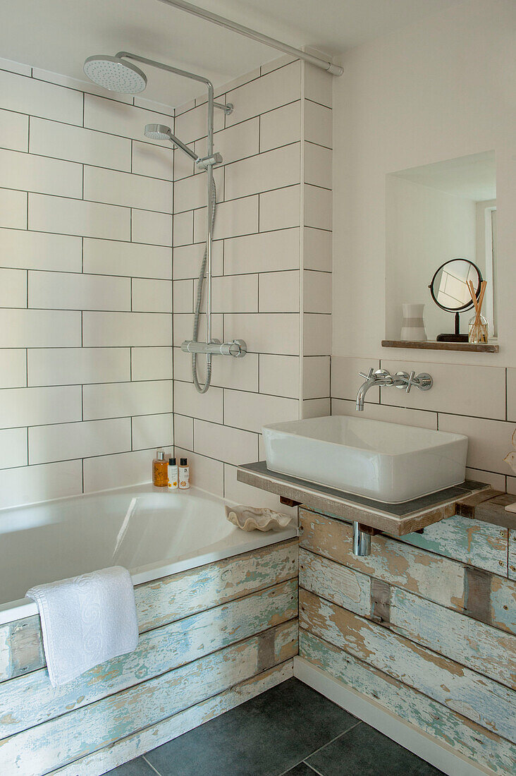 Duscharmatur in einem weiß gefliesten Badezimmer mit Holzverkleidung in Cornwall, Großbritannien
