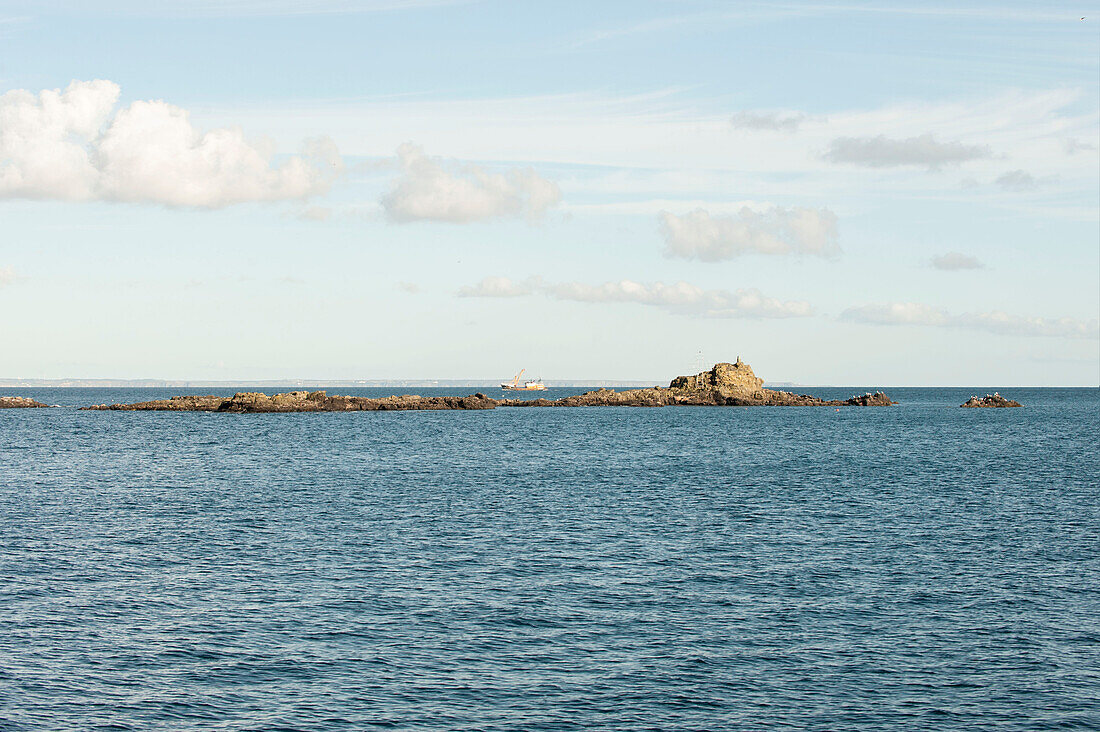 Rocky peninsula with boat on distant horizon Cornwall UK