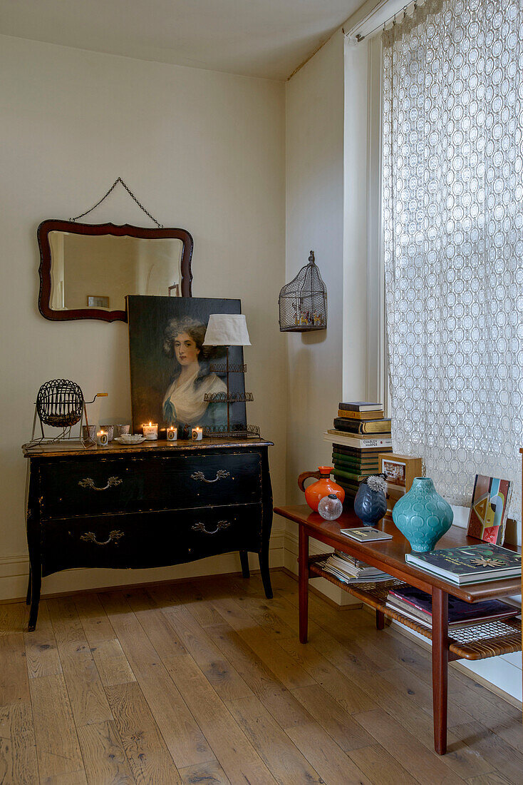 Vasen und Bücher auf einem Tisch mit Sideboard und geschlossenen Gardinen in einem Londoner Haus UK