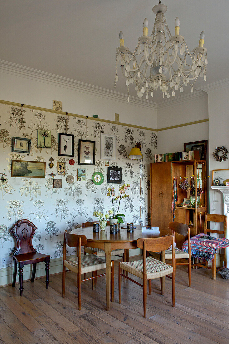 Kronleuchter und Bilderwand mit Vintage-Tisch im Esszimmer eines Londoner Hauses, UK