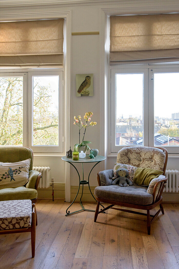 Vintage armchairs and footstool in windows of London apartment UK
