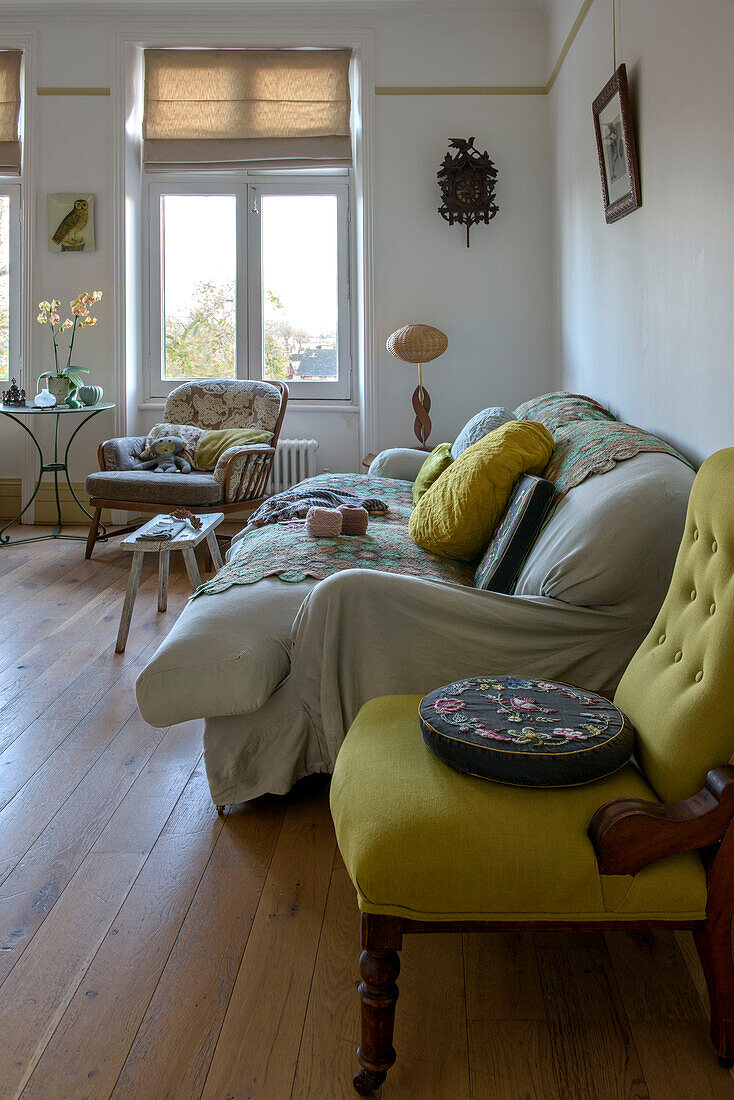 Gobelin-Kissen auf gelbem Stuhl mit cremefarbenem Sofa in einer Wohnung in London UK