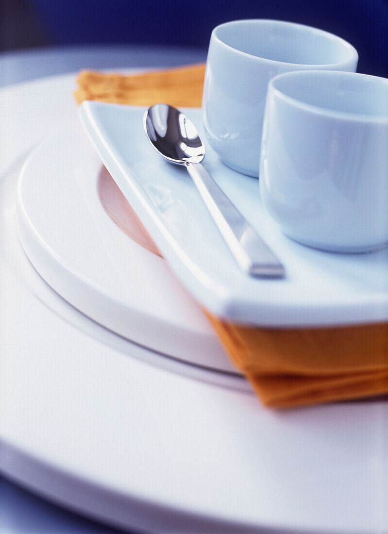 Coffee cups and spoon with napkin on plate