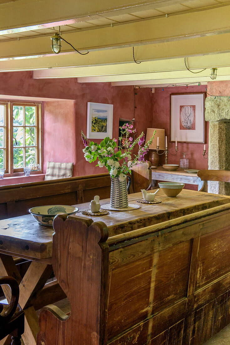 Cut flowers on old fashioned wooden bench seating and table in Helston farmhouse Cornwall UK