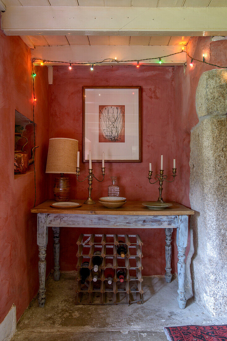 Kerzenständer auf einem Tisch mit Weinregal und Lichterketten in einem Bauernhaus in Helston, Cornwall, UK