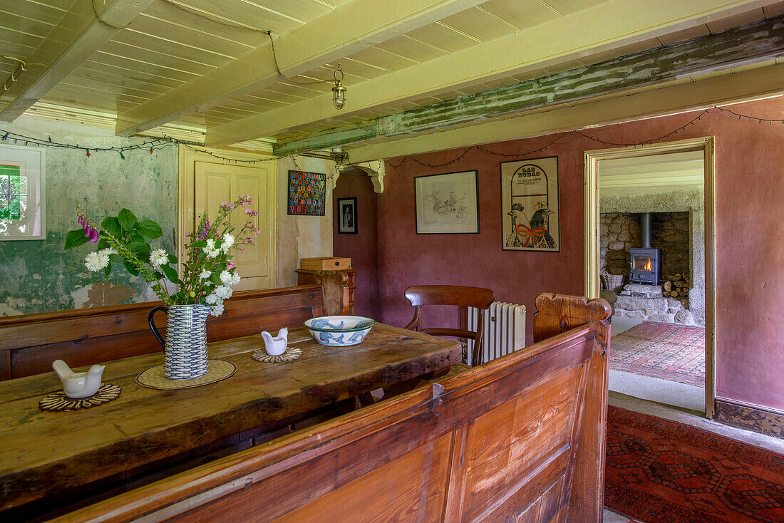 Altmodische Sitzbank und Tisch aus Holz mit Blick durch die Tür in einem Bauernhaus in Helston, Cornwall UK
