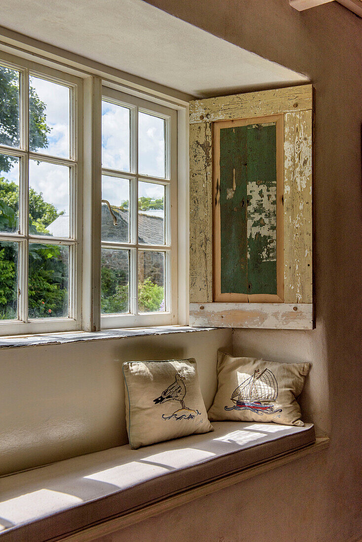 Fenstersitz mit bestickten Kissen in einem Bauernhaus in Helston, Cornwall, Großbritannien