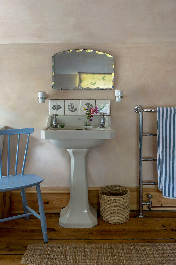 Vintage-Spiegel über einem Sockelwaschbecken mit gestreiften Handtüchern auf einer Chromleiste in einem Bauernhaus in Helston, Cornwall, UK