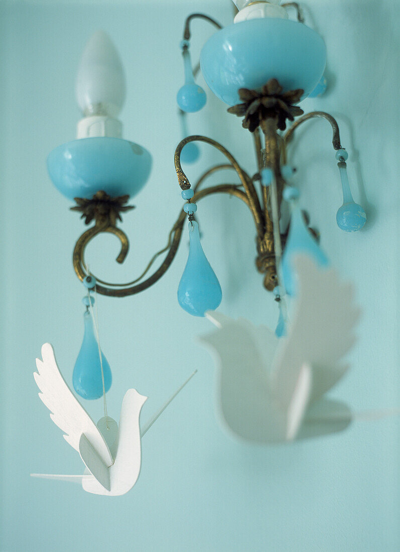 White paper doves as Easter decorations hanging from a blue glass wall light