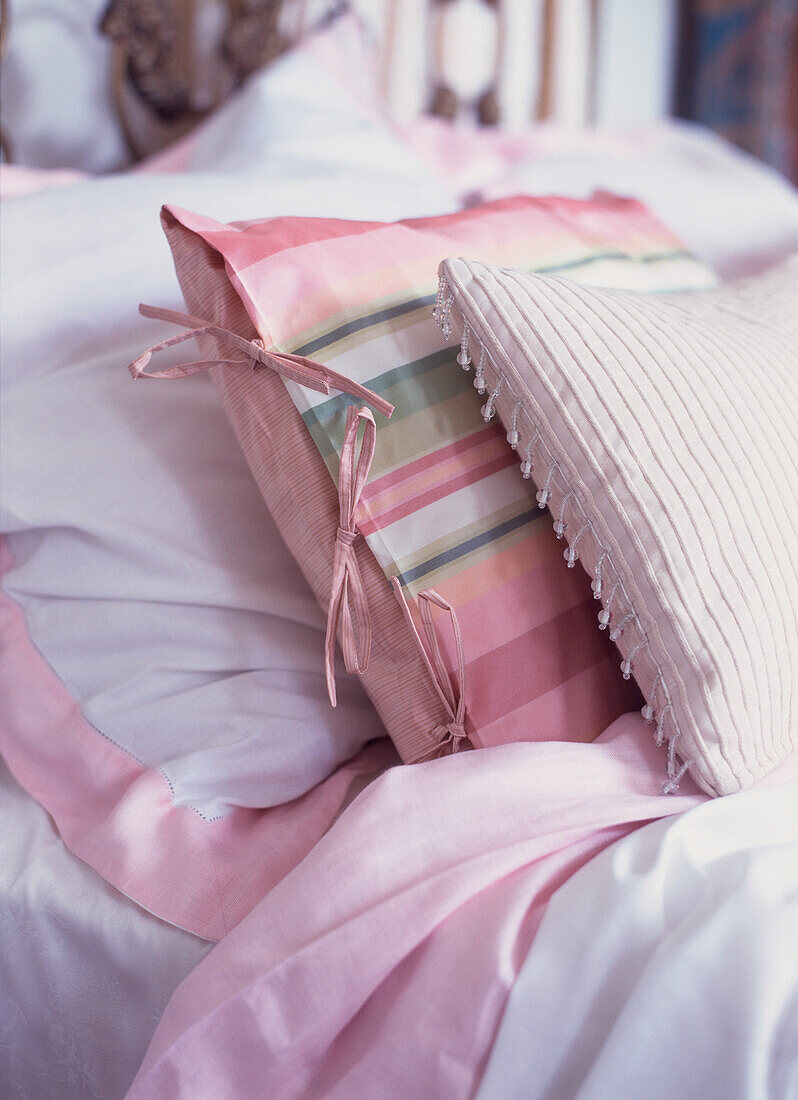 Nahaufnahme von hübschen Stoffkissen auf pastellfarbenem Bett