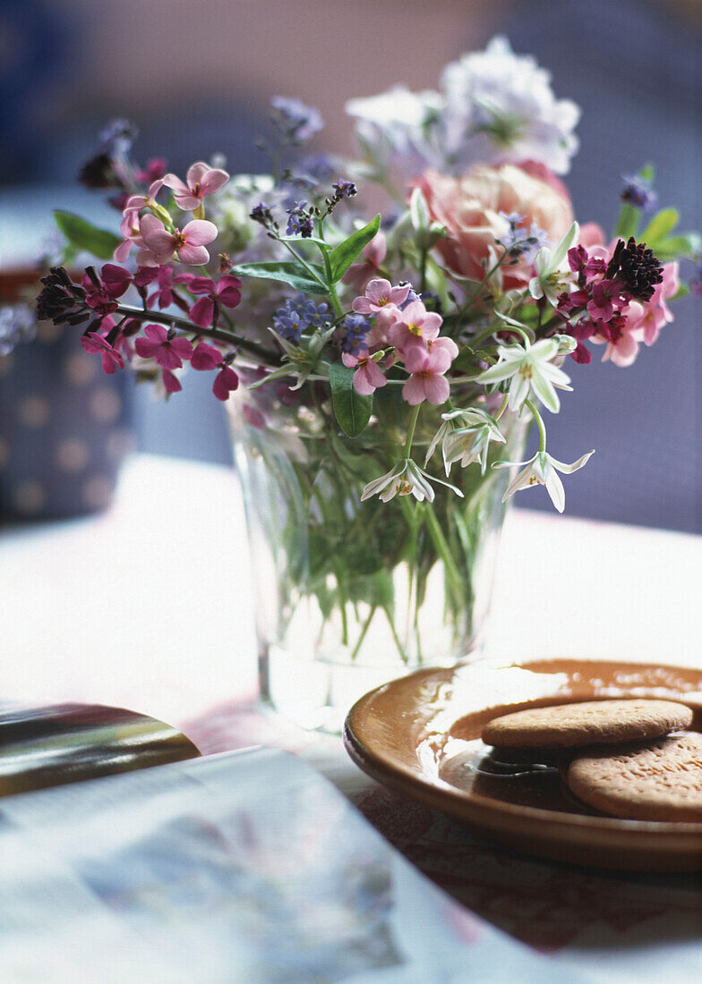 Wildflowers in glass vase with cookies on plate