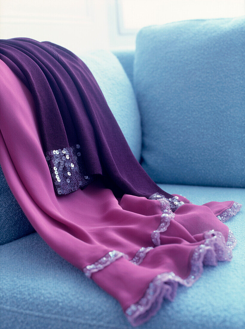 Purple and pink party clothes draped on blue sofa