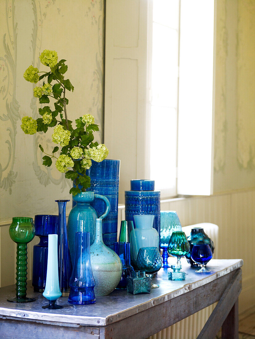 Sammlung blauer Glaswaren und Keramik mit gelber Blüte