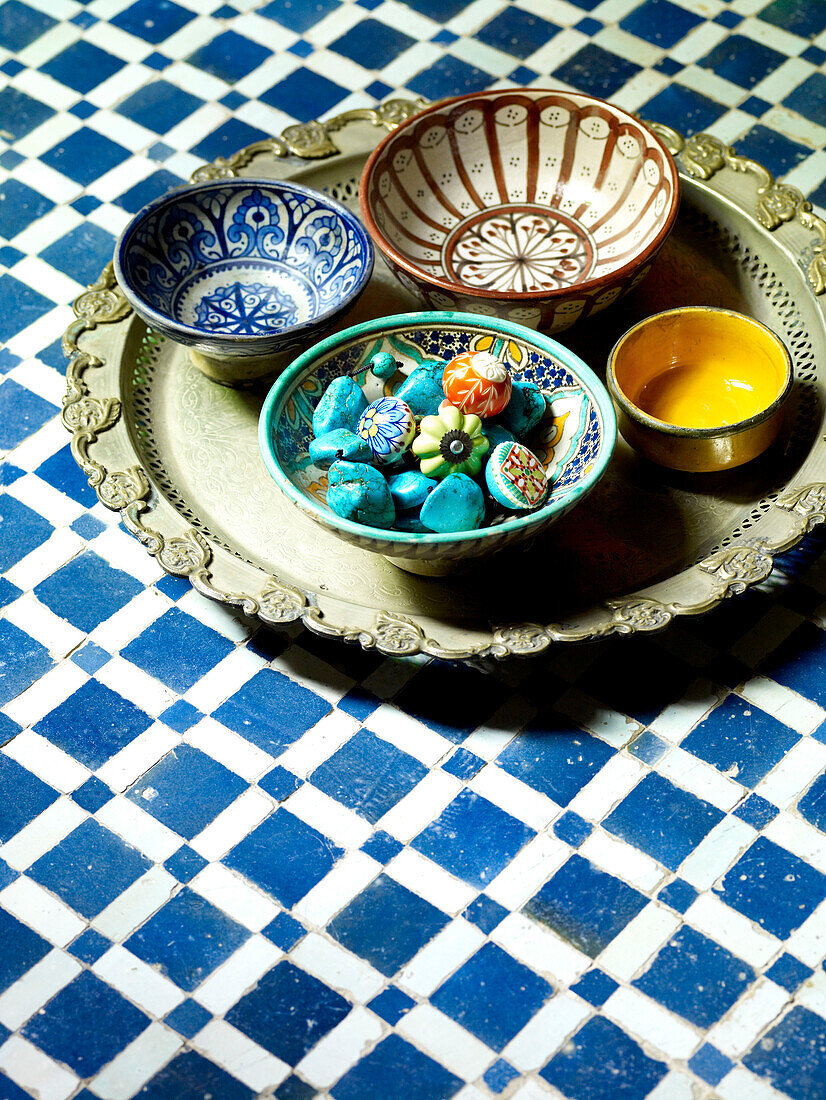 Turquoise gemstones in hand painted Moroccan bowls with tray on tabletop North Africa