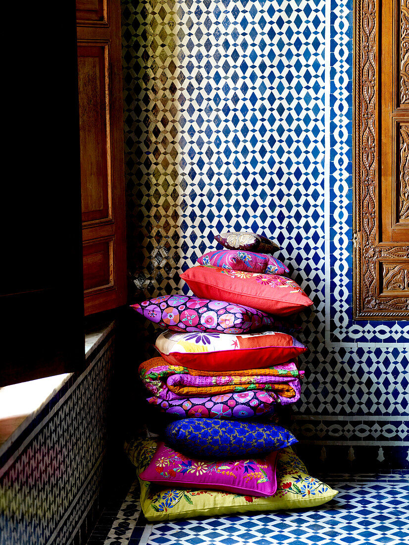 Helle Kissen und geometrische Kacheln in einem marokkanischen Riad in Nordafrika