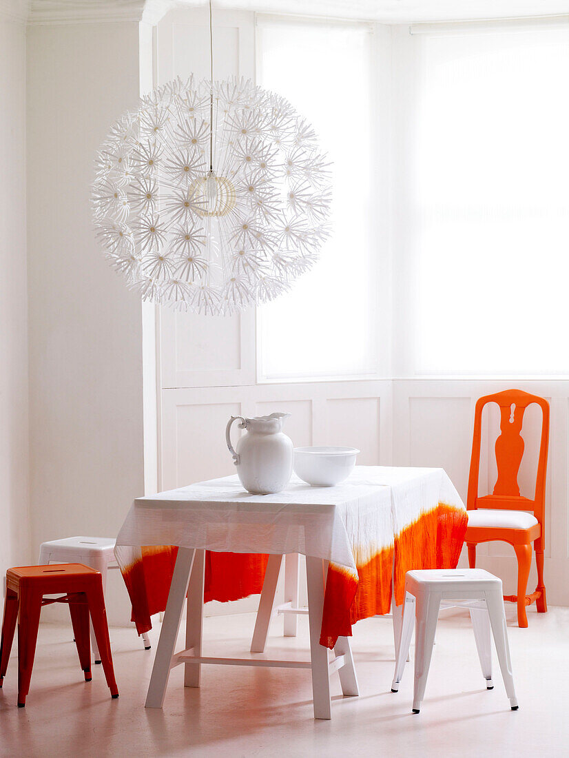 Tie-dyed tablecloth with orange chair in bright room