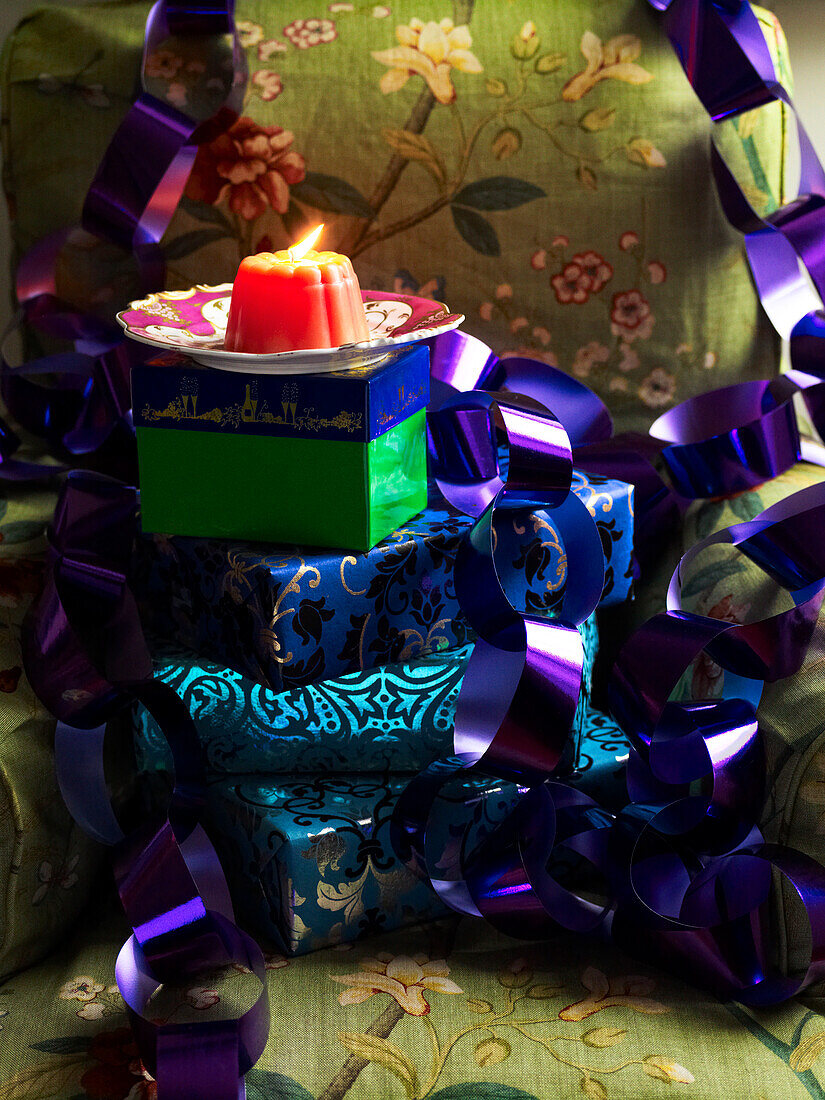 Lila Luftschlange und eingepackte Geschenke mit brennenden Kerzen in einem schottischen Haus, UK