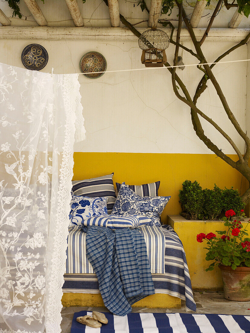 Blaue und weiße Stoffe mit Gardine auf der Veranda eines spanischen Hauses