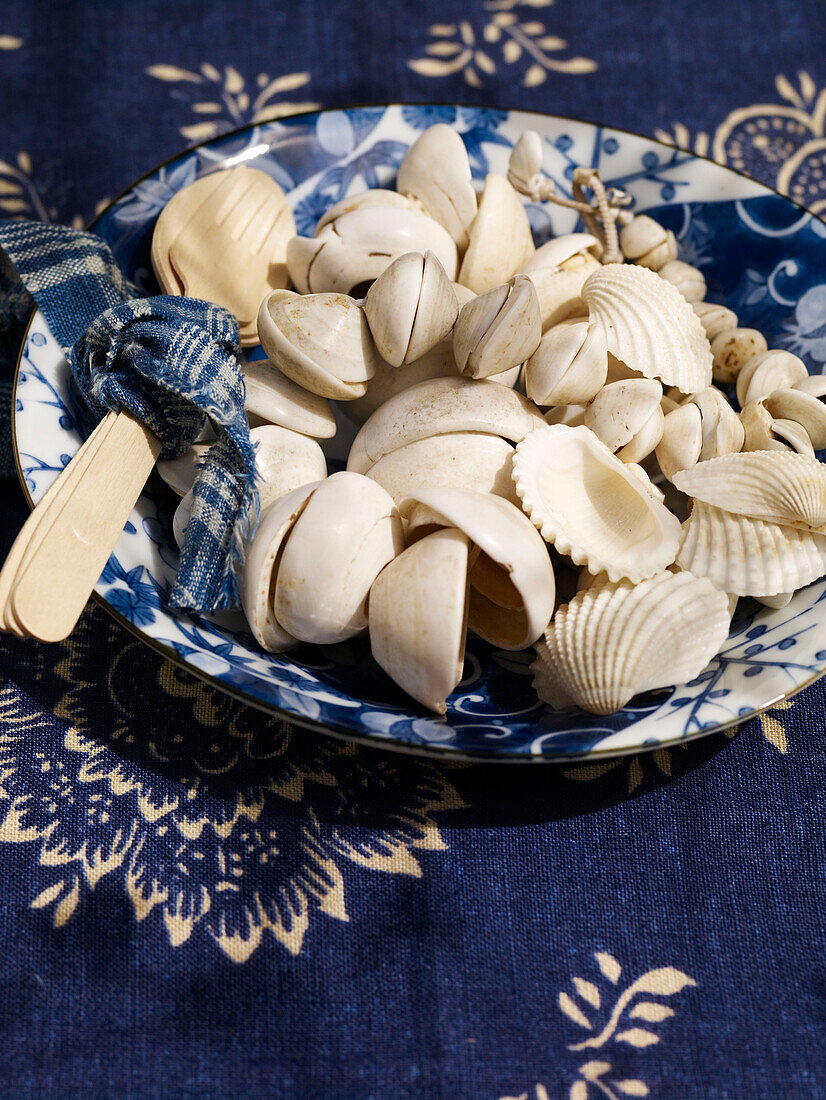 Muscheln auf blau-weißer Schale mit Holzgabel und -löffel Spanien