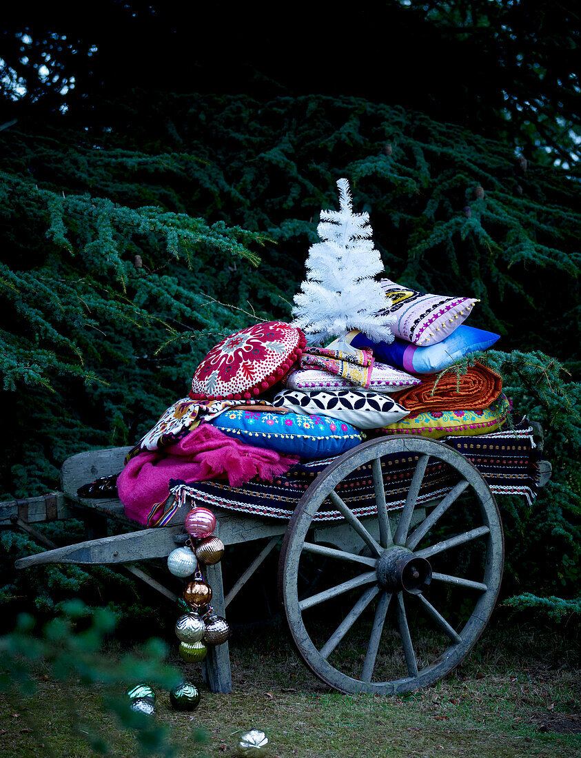 Weihnachtsbaum und mit Kugeln bestückte Kissen auf einem rustikalen Wagen