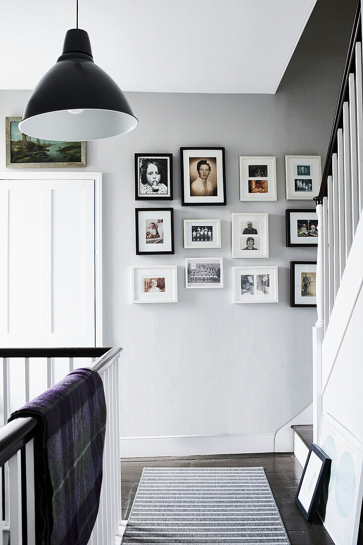 Picture wall and striped floor rug in staircase landing of Lyme Regis home Dorset UK