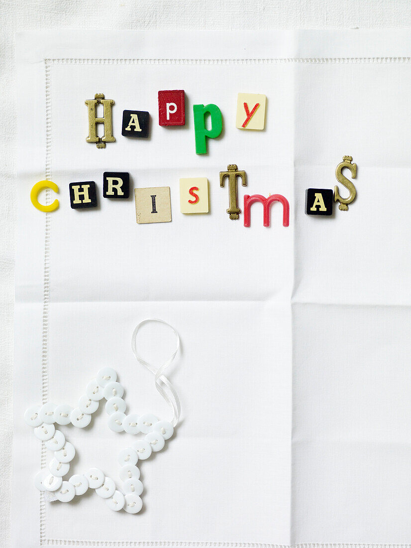 "Frohe Weihnachten in verschiedenen Buchstaben mit sternförmigem Knopfschmuck"""