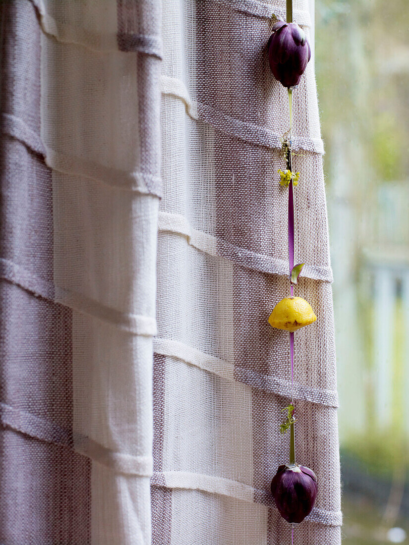 Lila Blumen hängen mit einem Band an einem Vorhang-Detail