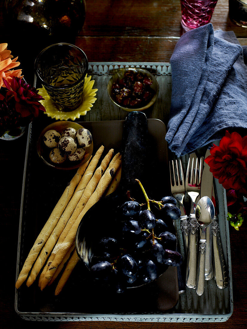 Tablett mit Brotstangen und Weintrauben auf Holztisch