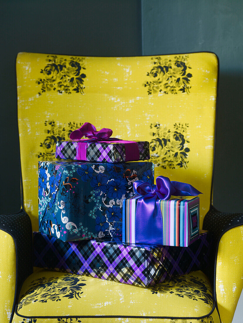 Vier eingepackte Geschenke auf einem gelben geblümten Sessel
