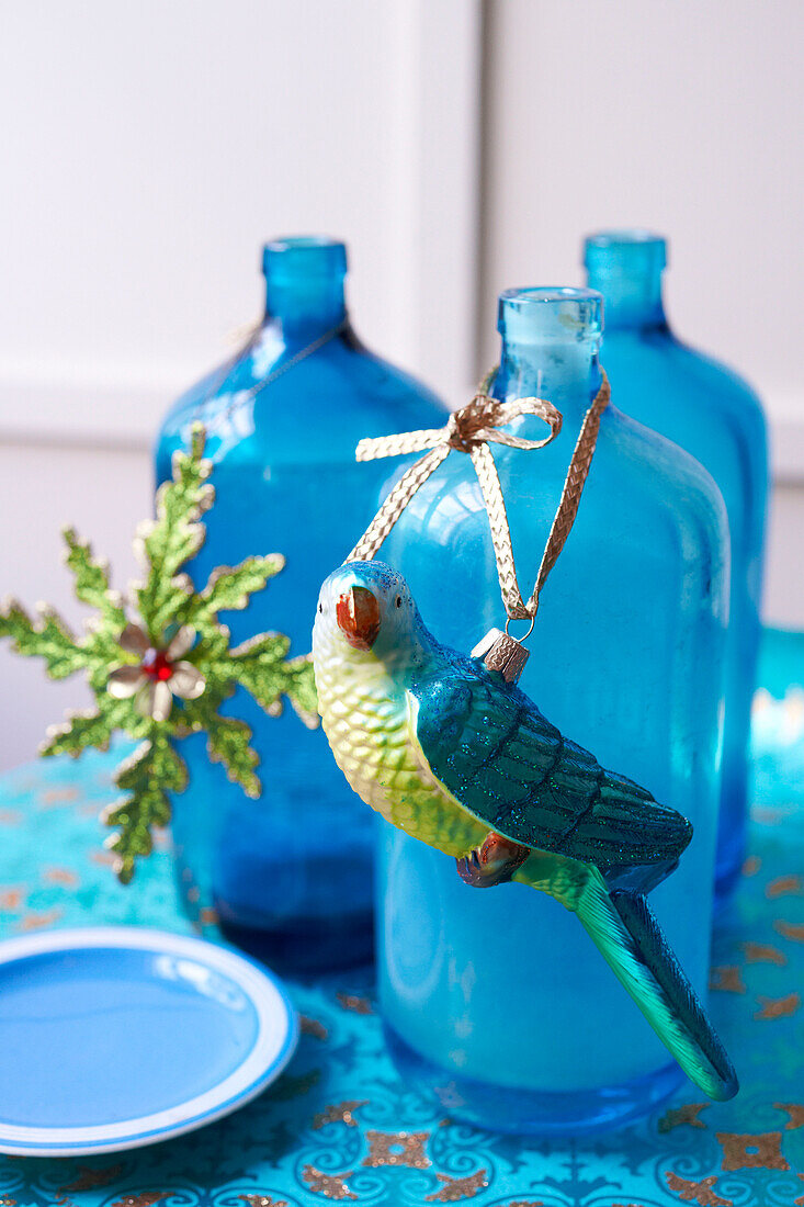Papageienkugel mit goldenem Band auf blaue Glasflasche gebunden