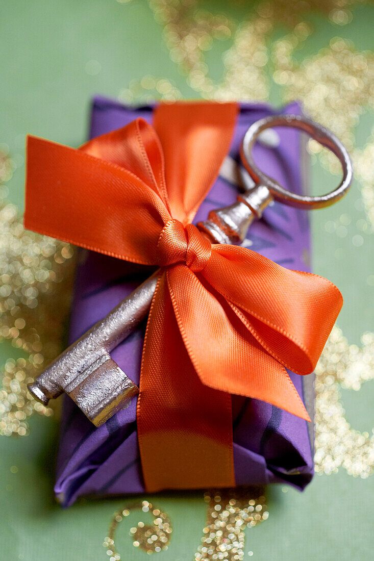 Silver key on small present tied with a ribbon