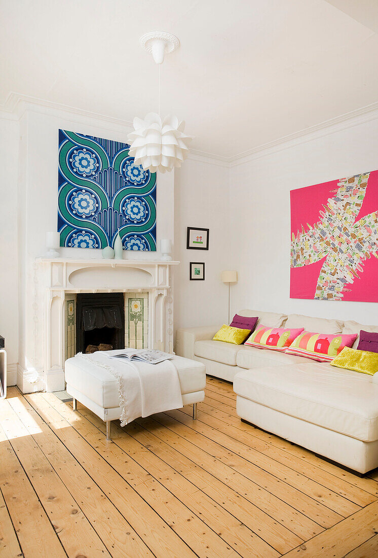 Weißes Ledersofa und farbenfrohe Kunstwerke im Wohnzimmer einer Familie in Manchester, England, UK