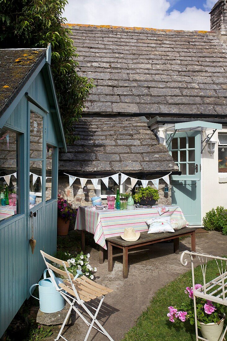 Picnic table and bench with bunting and shed in cottage garden, Corfe Castle, Dorset, England, UK